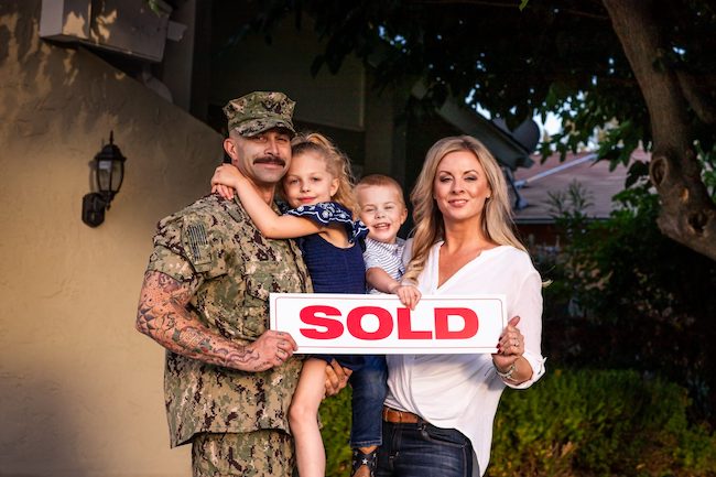 Military family holding a sold sign