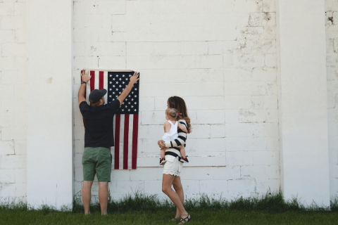 A man holding the United States flag on the side of a wall
